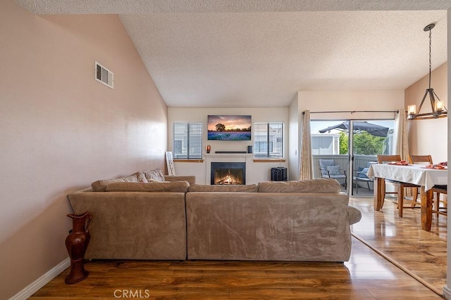 27066 Hidaway Ave Unit 6, Canyon Country, CA 91351 - living area with wood finished floors, a textured ceiling, a warm lit fireplace, lofted ceiling, and a chandelier