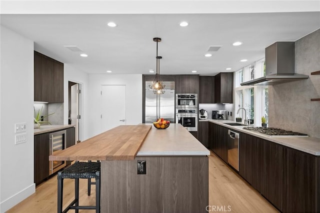 1061 Skyline Dr, Laguna Beach, CA 92651 - kitchen featuring appliances with stainless steel finishes, wine cooler, wall chimney range hood, light wood finished floors, and light countertops