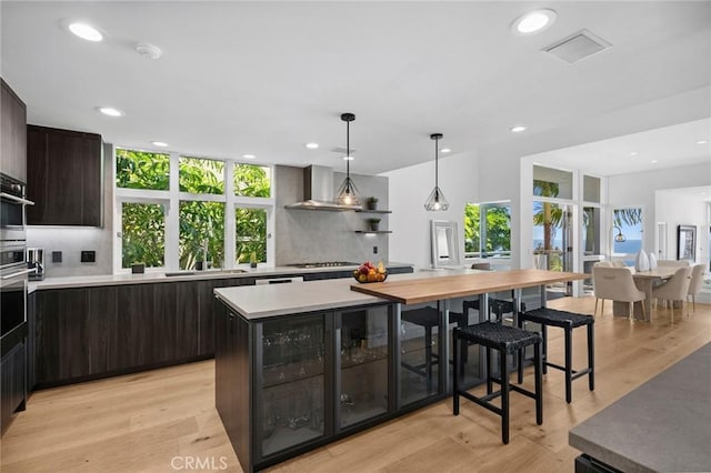 1061 Skyline Dr, Laguna Beach, CA 92651 - kitchen featuring wall chimney range hood, tasteful backsplash, light countertops, recessed lighting, and dark brown cabinetry