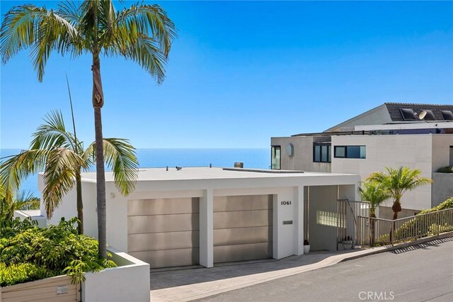 1061 Skyline Dr, Laguna Beach, CA 92651 - view of front facade featuring stucco siding, an attached garage, a water view, and driveway