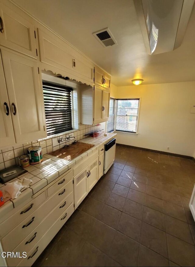 701 Francis St, Bakersfield, CA 93303 - kitchen featuring tile counters, dishwasher, decorative backsplash, dark tile patterned flooring, and white cabinets