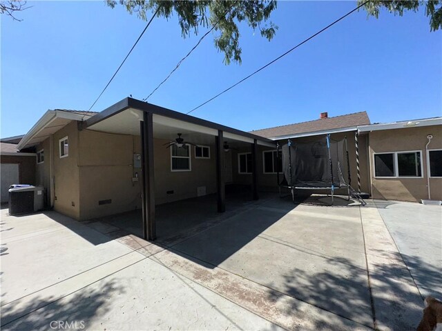 9387 Frankfort Ave, Fontana, CA 92335 - rear view of property featuring a trampoline, a ceiling fan, crawl space, stucco siding, and a patio area