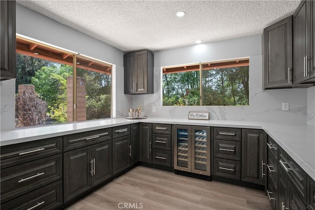 18561 Bert Rd, Riverside, CA 92508 - kitchen with wine cooler, a textured ceiling, plenty of natural light, light wood-style flooring, and light countertops