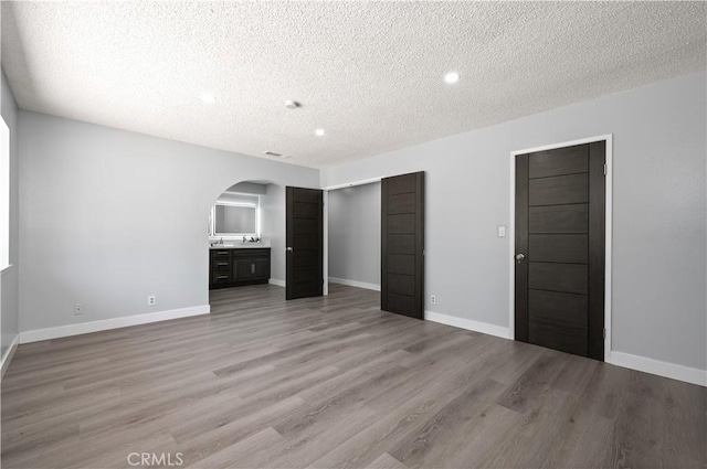 18561 Bert Rd, Riverside, CA 92508 - unfurnished bedroom featuring arched walkways, a textured ceiling, light wood-type flooring, and recessed lighting
