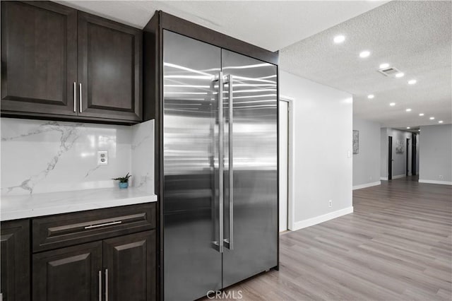 18561 Bert Rd, Riverside, CA 92508 - kitchen featuring stainless steel built in refrigerator, a textured ceiling, light wood finished floors, tasteful backsplash, and dark brown cabinets