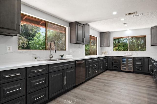 18561 Bert Rd, Riverside, CA 92508 - kitchen with beverage cooler, dishwasher, a textured ceiling, light wood-style flooring, and backsplash
