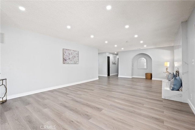 18561 Bert Rd, Riverside, CA 92508 - unfurnished living room featuring arched walkways, recessed lighting, light wood-type flooring, and a textured ceiling