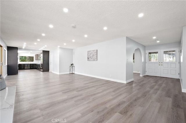 18561 Bert Rd, Riverside, CA 92508 - unfurnished living room featuring wood finished floors, recessed lighting, arched walkways, a textured ceiling, and healthy amount of natural light