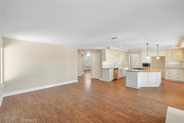 31752 Poole Ct, Temecula, CA 92591 - kitchen featuring light wood-style floors, appliances with stainless steel finishes, decorative backsplash, glass insert cabinets, and open floor plan