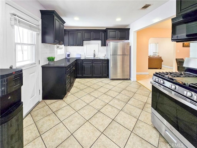 9313 Dearborn Ave, South Gate, CA 90280 - kitchen with stainless steel appliances, dark countertops, decorative backsplash, light tile patterned floors, and recessed lighting