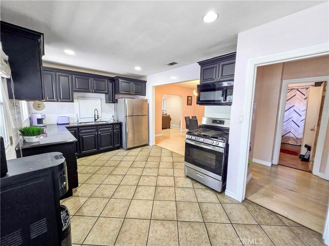 9313 Dearborn Ave, South Gate, CA 90280 - kitchen featuring appliances with stainless steel finishes, light tile patterned flooring, recessed lighting, arched walkways, and decorative backsplash