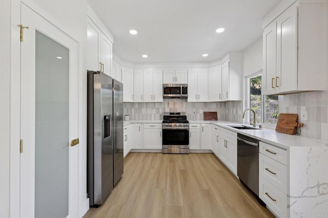 5471 Papagallo Dr, Oceanside, CA 92057 - kitchen featuring appliances with stainless steel finishes, light wood-style flooring, white cabinetry, light stone counters, and tasteful backsplash