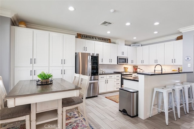 31735 Mesa View Dr, Menifee, CA 92584 - kitchen featuring appliances with stainless steel finishes, dark countertops, light wood-type flooring, backsplash, and white cabinets