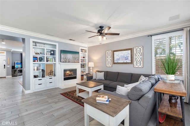 31735 Mesa View Dr, Menifee, CA 92584 - living area with ornamental molding, light wood finished floors, ceiling fan, built in shelves, and a lit fireplace