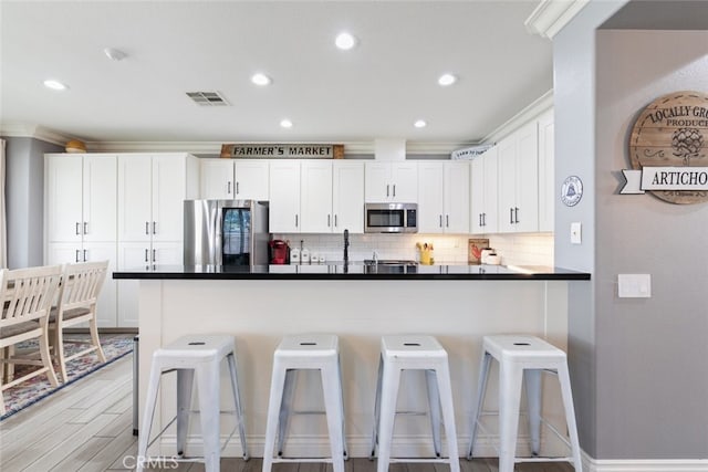 31735 Mesa View Dr, Menifee, CA 92584 - kitchen with appliances with stainless steel finishes, dark countertops, white cabinets, backsplash, and recessed lighting