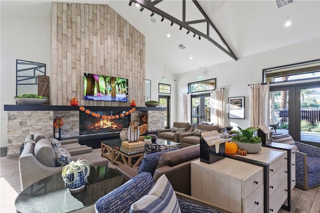 32813 Brunello Way, Temecula, CA 92591 - living area featuring wood finished floors, high vaulted ceiling, a stone fireplace, and french doors