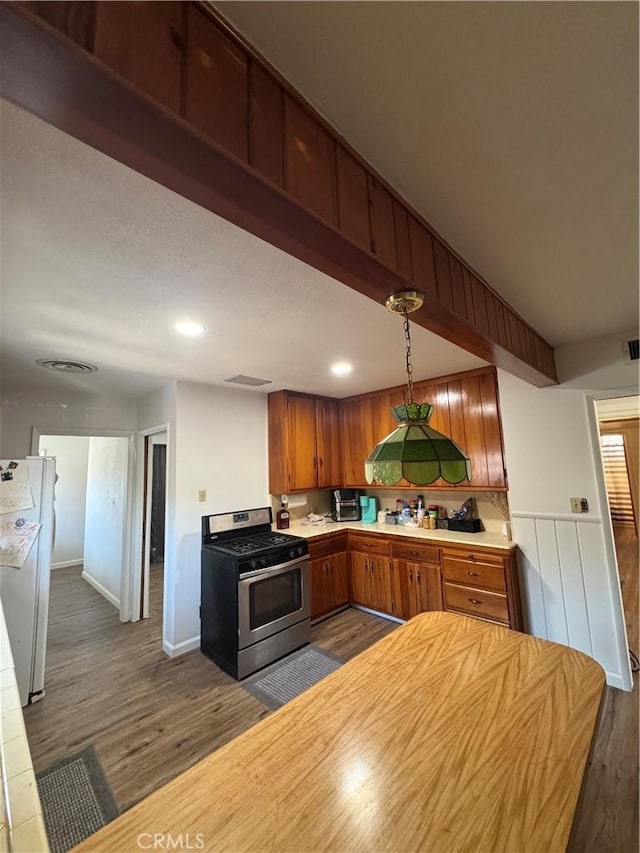 1004 Paloma St, Bakersfield, CA 93304 - kitchen featuring gas range, freestanding refrigerator, dark wood-style flooring, light countertops, and brown cabinets