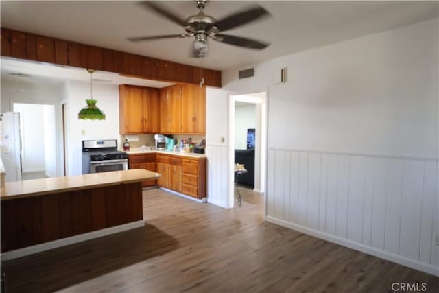 1004 Paloma St, Bakersfield, CA 93304 - kitchen featuring stainless steel range, wood finished floors, light countertops, a ceiling fan, and a wainscoted wall