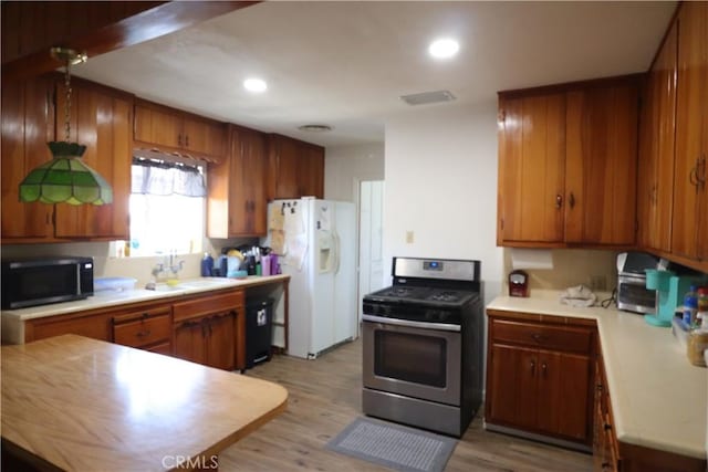 1004 Paloma St, Bakersfield, CA 93304 - kitchen with appliances with stainless steel finishes, light countertops, light wood-style flooring, brown cabinets, and recessed lighting