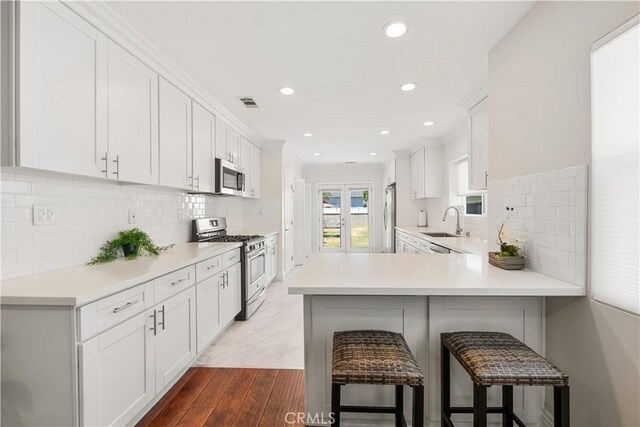 321 N Keystone St, Burbank, CA 91506 - kitchen with stainless steel appliances, a kitchen breakfast bar, dark wood finished floors, light countertops, and a peninsula