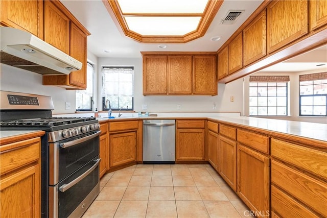 2911 Gilead Ln, Paso Robles, CA 93446 - kitchen with appliances with stainless steel finishes, under cabinet range hood, light tile patterned flooring, brown cabinetry, and recessed lighting