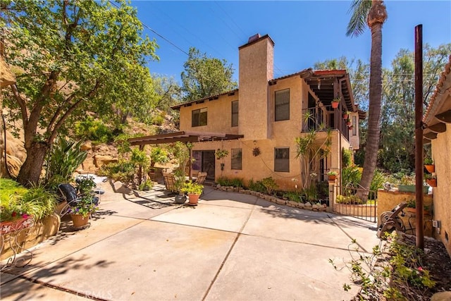 9349 Hartman Way, West Hills, CA 91304 - rear view of house with stucco siding, a chimney, and a patio area