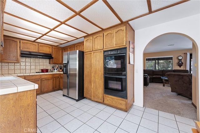 9349 Hartman Way, West Hills, CA 91304 - kitchen featuring stainless steel fridge, under cabinet range hood, tile counters, arched walkways, and light tile patterned floors