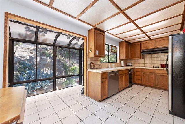 9349 Hartman Way, West Hills, CA 91304 - kitchen with stainless steel appliances, under cabinet range hood, brown cabinetry, and backsplash