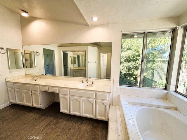 493 Hillsborough Way, Corona, CA 92879 - full bathroom featuring double vanity, a garden tub, wood finished floors, a textured ceiling, and vaulted ceiling