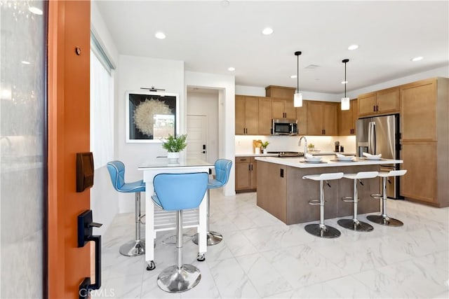 2371 Horseback Rd, Rancho Mission Viejo, CA 92694 - kitchen featuring stainless steel appliances, a kitchen bar, light countertops, a center island, and decorative light fixtures