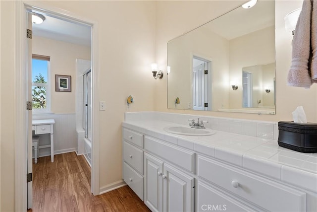 6600 San Gabriel Rd, Atascadero, CA 93422 - bathroom featuring wood finished floors, vanity, a wainscoted wall, and bath / shower combo with glass door