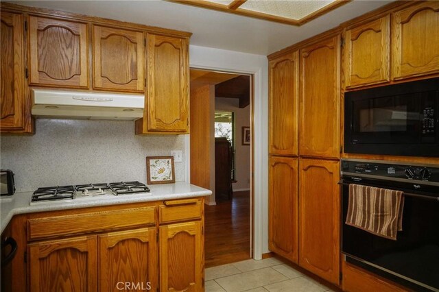 2787 Grape Way, Chico, CA 95973 - kitchen with black appliances, exhaust hood, brown cabinetry, and light countertops