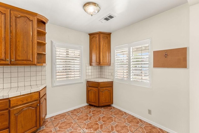 261 Twickenham Ave, Los Angeles, CA 90022 - kitchen featuring open shelves, tile counters, brown cabinetry, tasteful backsplash, and light tile patterned floors