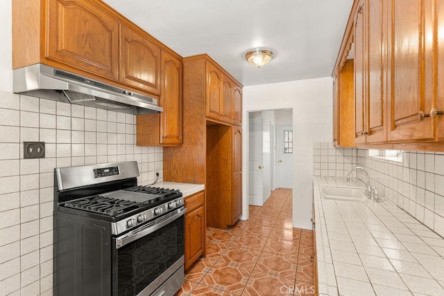 261 Twickenham Ave, Los Angeles, CA 90022 - kitchen featuring stainless steel gas stove, under cabinet range hood, light tile patterned flooring, and brown cabinets