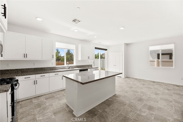30181 Adrift Ln, Menifee, CA 92584 - kitchen featuring range with gas stovetop, a center island, white cabinets, stone finish flooring, and dark stone counters