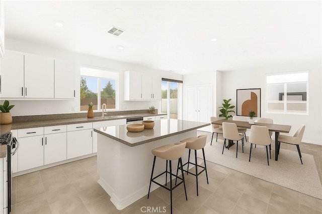 30181 Adrift Ln, Menifee, CA 92584 - kitchen featuring a breakfast bar, a kitchen island, white cabinets, gas range oven, and dark countertops