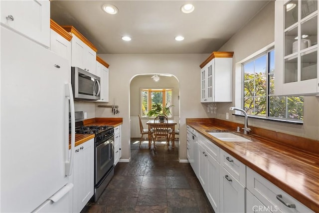 719 S Amstutz Ave, Anaheim, CA 92802 - kitchen featuring appliances with stainless steel finishes, wood counters, dark stone finish flooring, recessed lighting, and glass insert cabinets