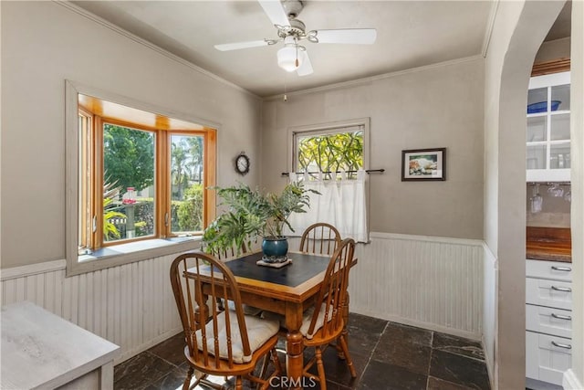 719 S Amstutz Ave, Anaheim, CA 92802 - dining space featuring wainscoting, a ceiling fan, arched walkways, stone tile floors, and ornamental molding