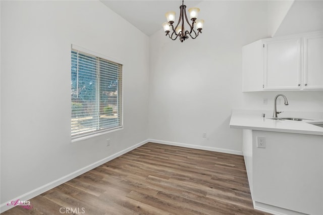 unfurnished dining area with a chandelier, wood finished floors, and lofted ceiling