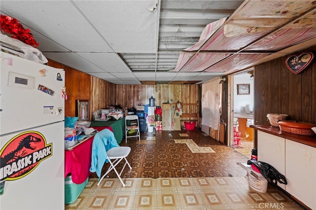 526 Nottingham Ave, Santa Ana, CA 92703 - basement featuring freestanding refrigerator, wood walls, tile patterned floors, and a paneled ceiling