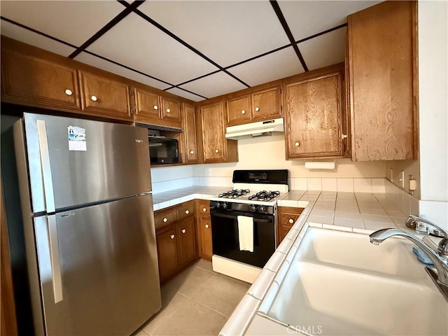 2402 Aviation Blvd Unit C, Redondo Beach, CA 90278 - kitchen featuring freestanding refrigerator, range with gas cooktop, under cabinet range hood, tile counters, and brown cabinetry