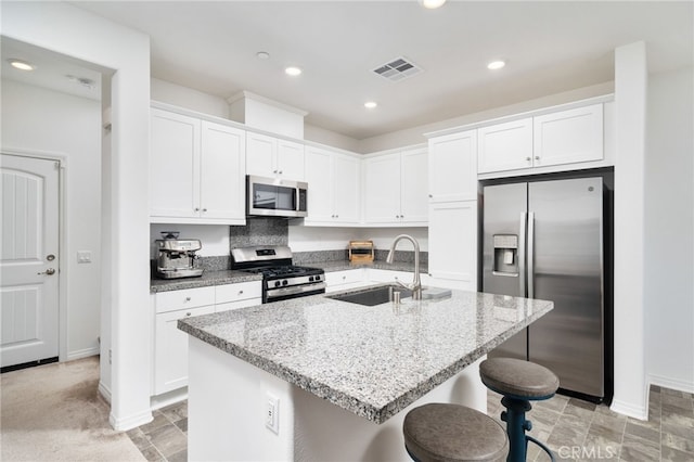 16502 Casa Grande Ave Unit 102, Fontana, CA 92336 - kitchen with appliances with stainless steel finishes, white cabinets, a kitchen breakfast bar, light stone counters, and an island with sink