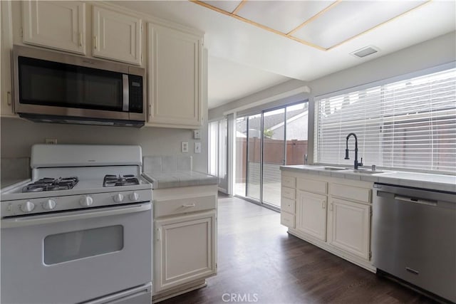 6186 Hefley St Unit 13, Westminster, CA 92683 - kitchen featuring appliances with stainless steel finishes, tile counters, dark wood-type flooring, and white cabinetry