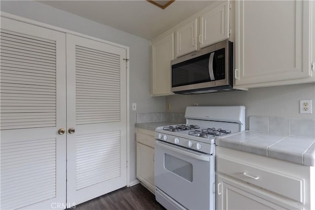 6186 Hefley St Unit 13, Westminster, CA 92683 - kitchen with stainless steel microwave, white gas range, tile countertops, dark wood-style flooring, and white cabinets