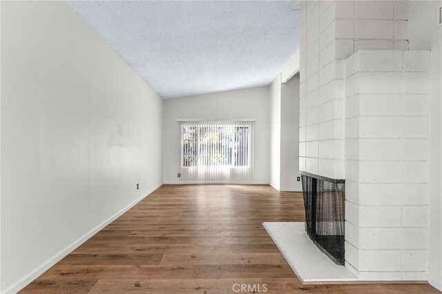 1204 San Jacinto, Redlands, CA 92373 - unfurnished living room featuring wood finished floors, a multi sided fireplace, a textured ceiling, and vaulted ceiling