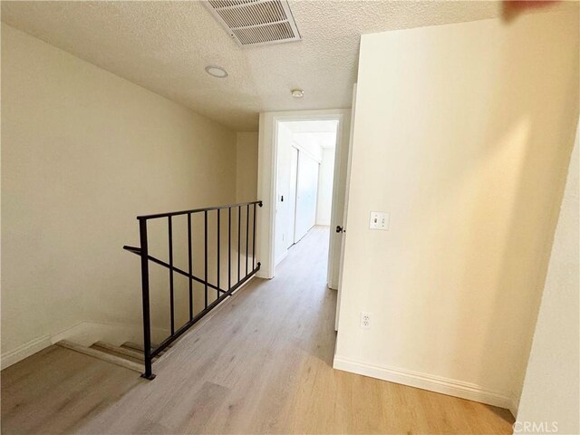 25180 5th St Unit 213, San Bernardino, CA 92410 - corridor with an upstairs landing, wood finished floors, and a textured ceiling