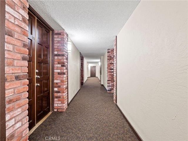 5334 Lindley Ave Unit 125, Encino, CA 91316 - hallway featuring dark carpet, a textured ceiling, and brick wall