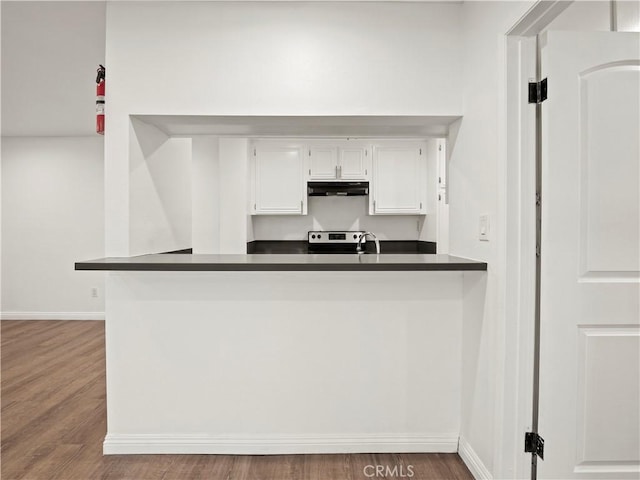 5334 Lindley Ave Unit 125, Encino, CA 91316 - kitchen with dark countertops, wood finished floors, white cabinetry, under cabinet range hood, and a peninsula