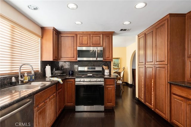 5266 Bluff St, Norco, CA 92860 - kitchen featuring appliances with stainless steel finishes, arched walkways, dark wood-style flooring, tasteful backsplash, and recessed lighting