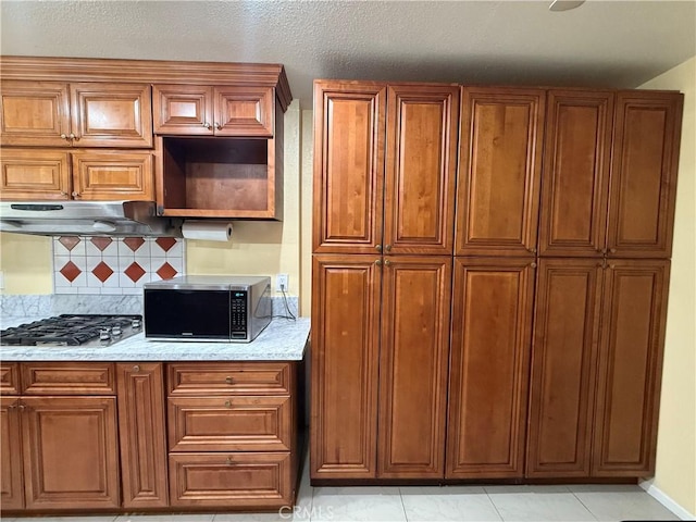 11057 Dudley Way, Stanton, CA 90680 - kitchen with appliances with stainless steel finishes, backsplash, brown cabinetry, and under cabinet range hood